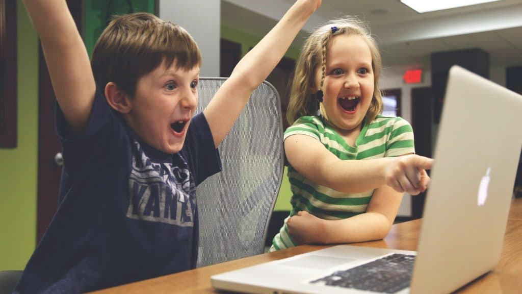 Boy and girl looking excitedly at a laptop