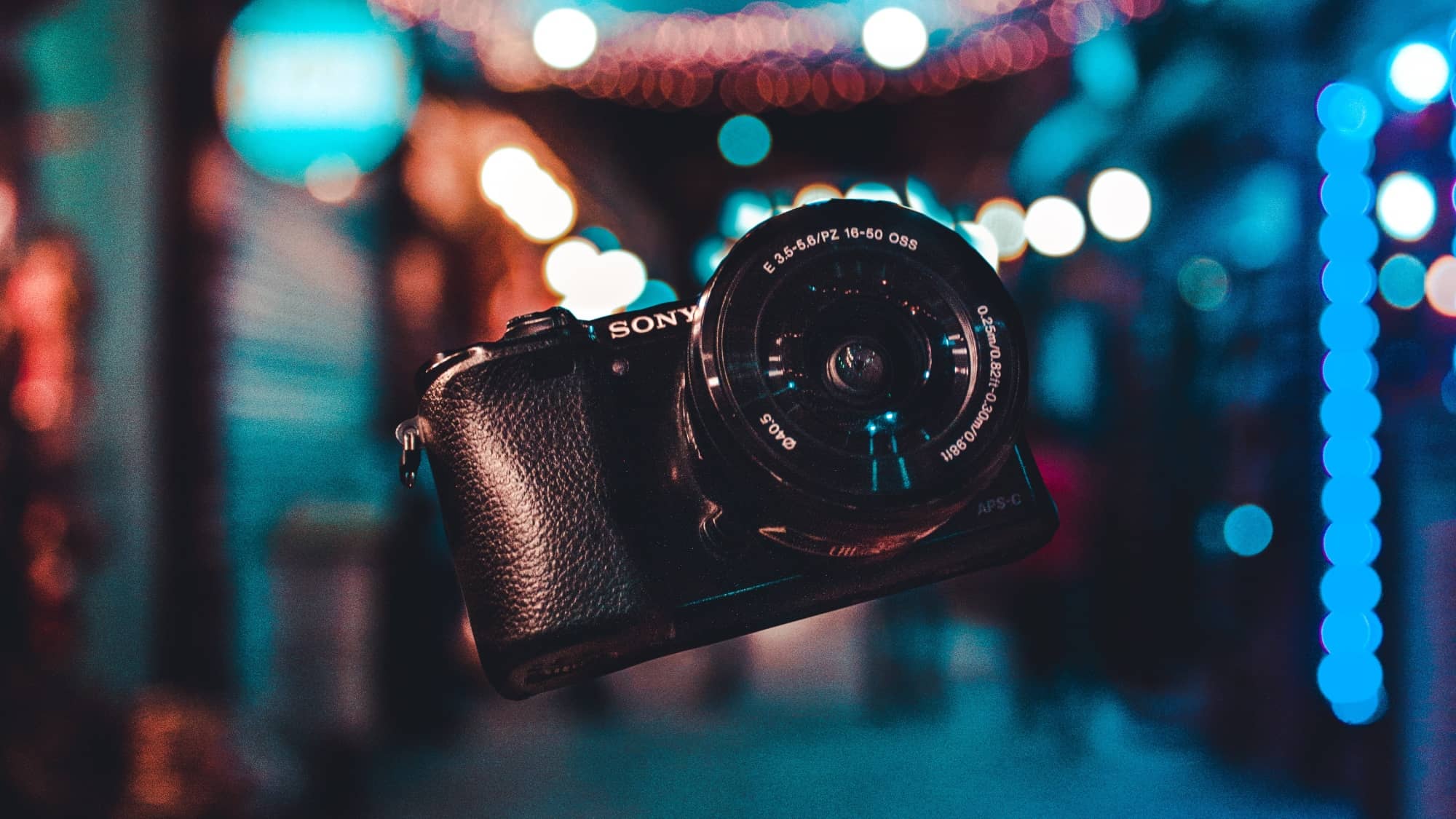 Black Sony camera floating in front of a lit street at night