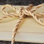 Hardback cream-covered book with a gold rope bow