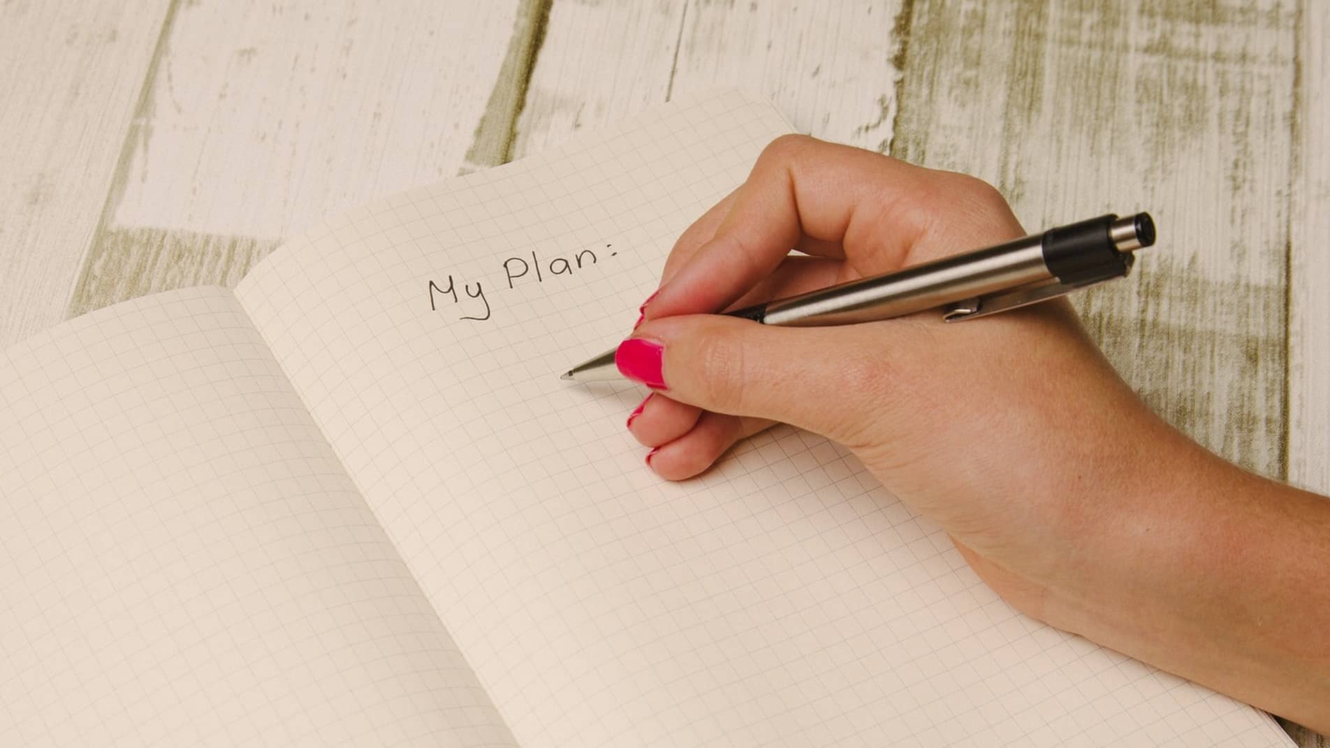 Handing holding pen over a notebook with words 'My Plan'