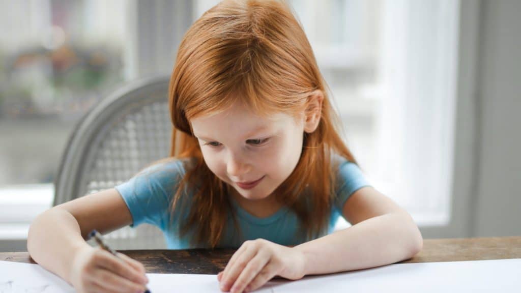 Young girl sat at table writing