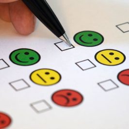 Pen hovering over feedback form with happy, indifferent and sad emojis
