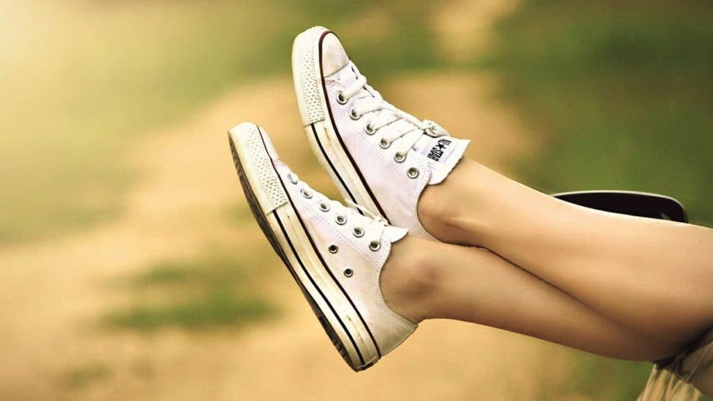 Feet wearing white Converse shoes