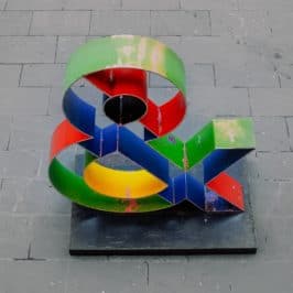 Colourful ampersand sculpture on grey pavement