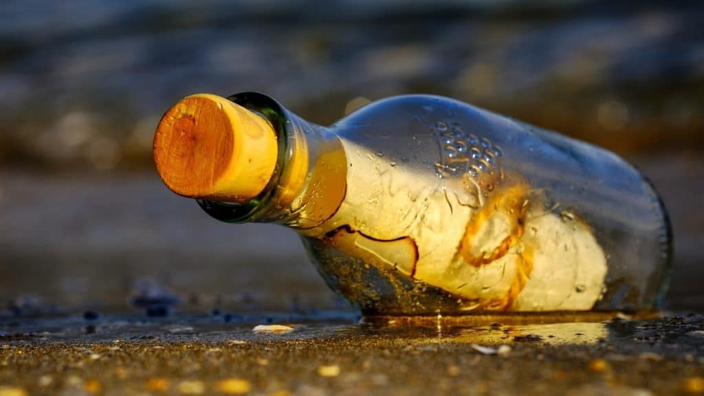 Stoppered bottle on shoreline with scrolled paper inside