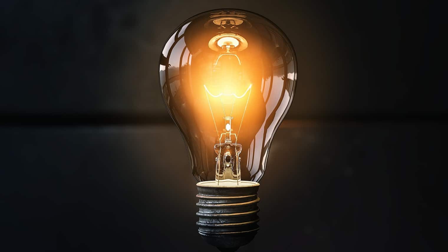 Lightbulb glowing orange against a black background