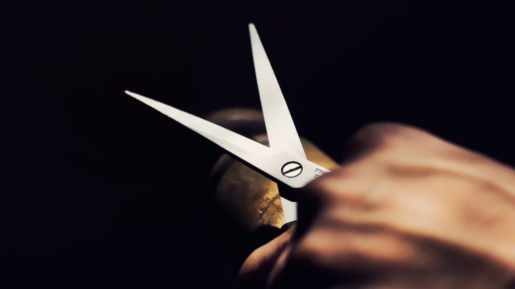 Open scissors held against a black background