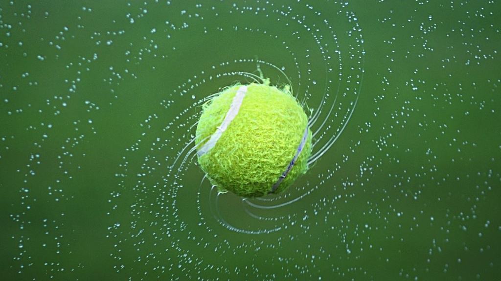 Spinning tennis ball, dispersing water droplets