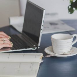 Hands typing on laptop, cup of coffee alongside