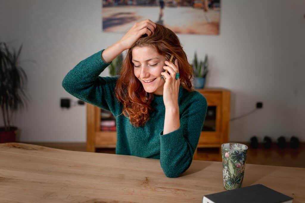 Woman with long wavy ginger hair on phone, smiling