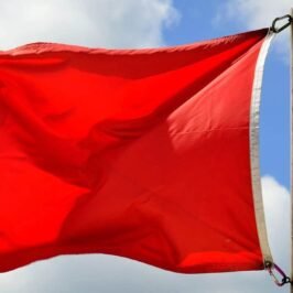 Red flag flying against a blue sky with white clouds